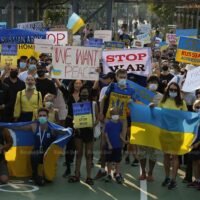 Ukrainer halten am Sonntag bei einem Marsch vom Lumpini Park zum Benjakitti Park im Zentrum von Bangkok Plakate und Nationalflaggen hoch.