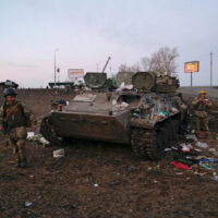 Ukrainische Soldaten werden am Donnerstag außerhalb von Charkiw in der Ukraine neben einem zerstörten gepanzerten Fahrzeug gesehen, von dem sie sagten, es gehöre der russischen Armee