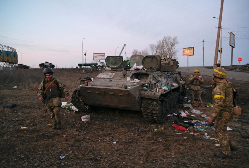 Ukrainische Soldaten werden am Donnerstag außerhalb von Charkiw in der Ukraine neben einem zerstörten gepanzerten Fahrzeug gesehen, von dem sie sagten, es gehöre der russischen Armee