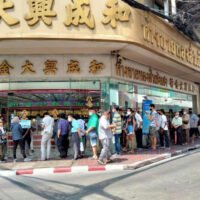 Menschen stehen am Montag in einer langen Schlange vor einem Goldgeschäft im Stadtteil Yaowarat in Bangkok. Die meisten verkauften ihr Gold,