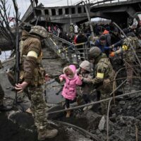 Menschen überqueren eine zerstörte Brücke, als sie die Stadt Irpin nordwestlich von Kiew evakuieren,