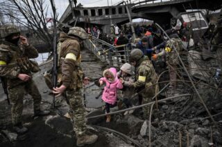 Menschen überqueren eine zerstörte Brücke, als sie die Stadt Irpin nordwestlich von Kiew evakuieren,