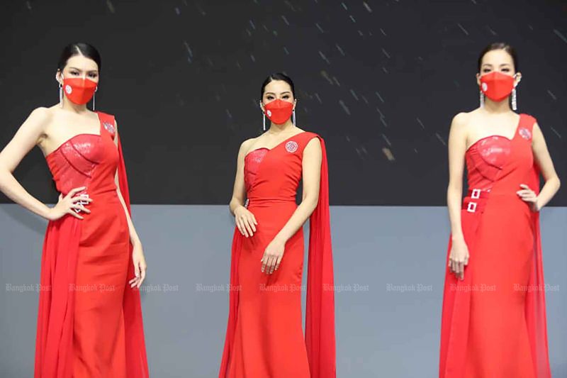 Models tragen auf der Bangkok International Motor Show 2022 in Nonthaburi farblich abgestimmte Gesichtsmasken, die den Covid-19-Kontrollen entsprechen.