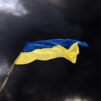 Rauch steigt hinter einer ukrainischen Flagge auf, nachdem russische Angriffe ein Treibstofflager in der Stadt Kalynivka getroffen haben.