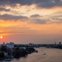 Am 4. April 2022 fahren Boote auf dem Fluss Chao Phraya, während die Sonne in Bangkok untergeht.