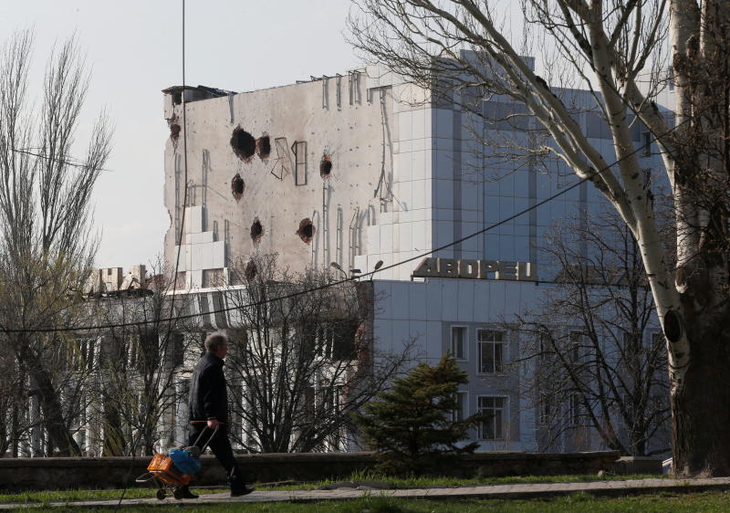 Ein Anwohner geht am Freitag an dem während des Ukraine-Russland-Konflikts beschädigten Kulturpalast in der südlichen Hafenstadt Mariupol in der Ukraine vorbei.