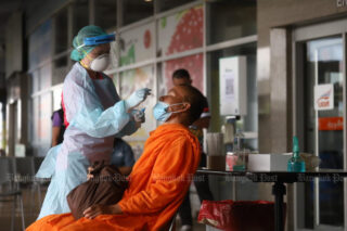 Ein Gesundheitshelfer führt am Donnerstag an einem Busbahnhof in Bangkok einen Abstrich-Antigentest bei einem Mönch durch