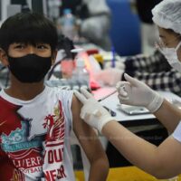 Ein Kind zeigt während seiner Covid-19-Impfung an der Bang Sue Grand Station in Bangkok ein V-Zeichen.