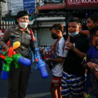 Ein Polizist hält Wasserpistolen in der Hand, nachdem er sie von den Jungen auf der Khao San Road beschlagnahmt hatte