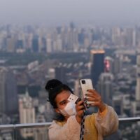 Eine Frau, die während des Ausbruchs von Covid-19 eine Gesichtsmaske trägt, macht am Mittwoch auf dem gläsernen Skywalk auf der Aussichtsplattform des King Power MahaNakhon - Gebäudes ein Selfie