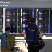 Flugreisende schauen am 1. April 2022 auf eine elektronische Fluginformationstafel am Flughafen Suvarnabhumi.