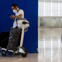 Passagiere warten am 1. Februar 2022 mit ihrem Gepäck am Flughafen Suvarnabhumi, während Thailand sein Quarantäneprogramm für freie Reisen für geimpfte Reisende wieder aufnimmt