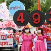 Arbeiter halten die Nummer 492 hoch, die Höhe des neuen täglichen Mindestlohns in Baht, den sie fordern,