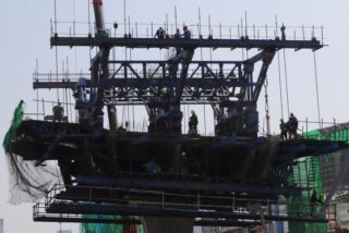 Arbeiter werden beim Zusammenbau einer Überführung an der Kreuzung Na Ranong gesehen. Bauarbeiter werden nach Tageslöhnen bezahlt – ein Betrag, der seit zwei Jahren nicht mehr gestiegen ist