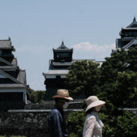 Besucher, die Gesichtsschutzmasken tragen, gehen am Mittwoch an der Burg Kumamoto in Kumamoto, Japan, vorbei.