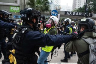 Die Polizei drängt eine Gruppe von Journalisten, nachdem sie eine Menschenmenge zerstreut hat