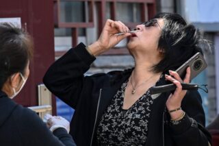 Eine Frau führt am Samstag in einem Gemeindezentrum in Peking einen Antigen Schnelltest für Covid-19 durch, während sie ein Smartphone in der Hand hält