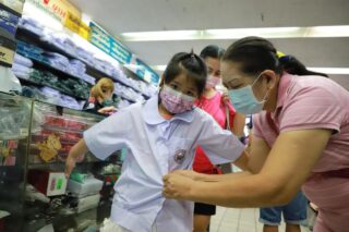 Einem Mädchen wird am Mittwoch in einem Geschäft in der Nähe des Paknam Marktes in Samut Prakan geholfen, eine Schuluniform anzuprobieren