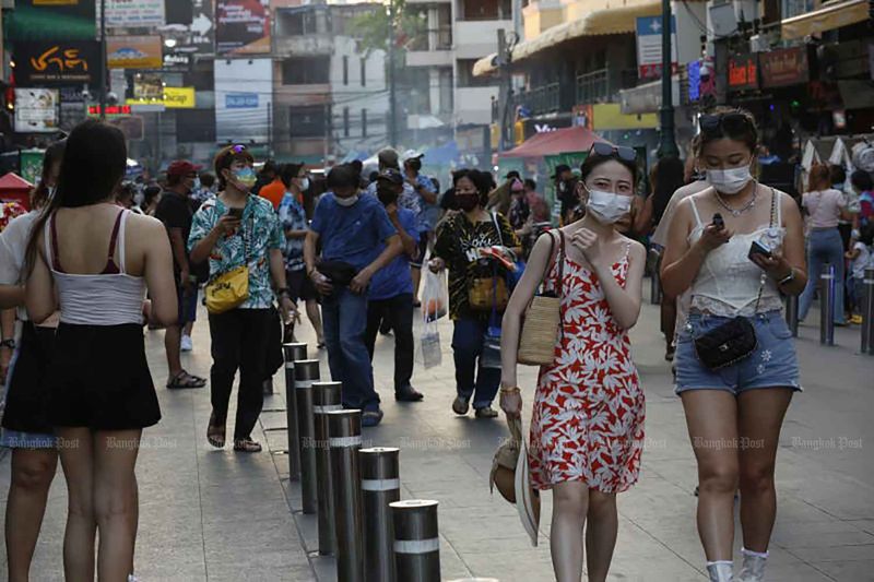 Menschen tragen Gesichtsmasken, wenn sie Mitte April während Songkran, dem traditionellen thailändischen Neujahr, die Khao San Road in Bangkok besuchen.