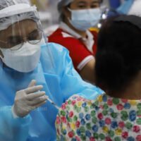 Ein Angehöriger der Gesundheitsberufe impft am 5. Juni an der Bang Sue Grand Station in Bangkok eine Frau gegen Covid-19