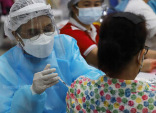 Ein Angehöriger der Gesundheitsberufe impft am 5. Juni an der Bang Sue Grand Station in Bangkok eine Frau gegen Covid-19