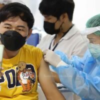 Ein Mann macht ein Selfie, während er an der Bang Sue Grand Station in Bangkok gegen Covid-19 geimpft wird.
