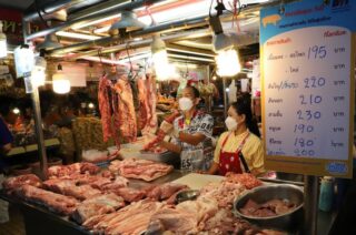 Ein Verkäufer auf dem Frischmarkt Bang Yai in Nonthaburi zeigt höhere Schweinefleischpreise an
