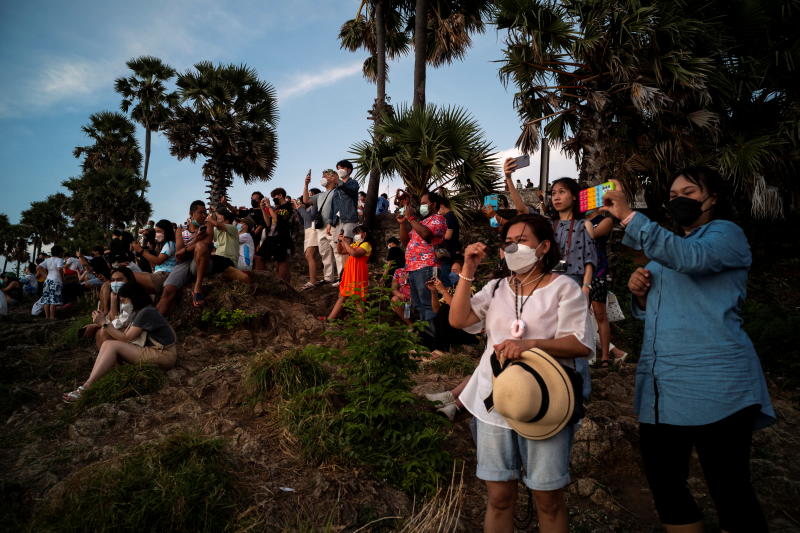 Einheimische und Touristen mit Schutzmasken beobachten am 9. April 2022 einen Sonnenuntergang vom Kap Phromthep in Phuket