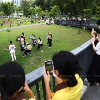 Menschen, die Gesichtsmasken tragen, sehen sich Anfang dieses Monats eine musikalische Darbietung im Benjakitti Park in Bangkok an