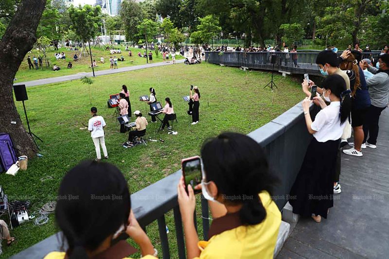 Menschen, die Gesichtsmasken tragen, sehen sich Anfang dieses Monats eine musikalische Darbietung im Benjakitti Park in Bangkok an