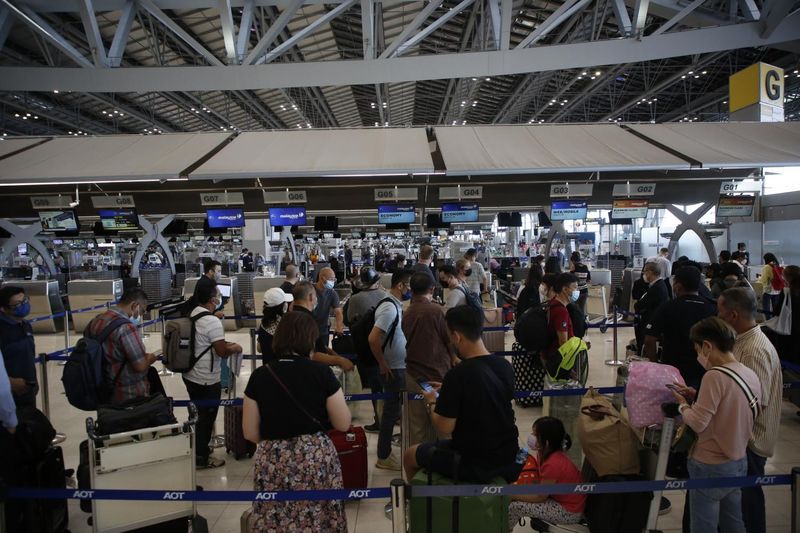 Passagiere stehen am Flughafen Suvarnabhumi Schlange, um für ihren Flug einzuchecken.
