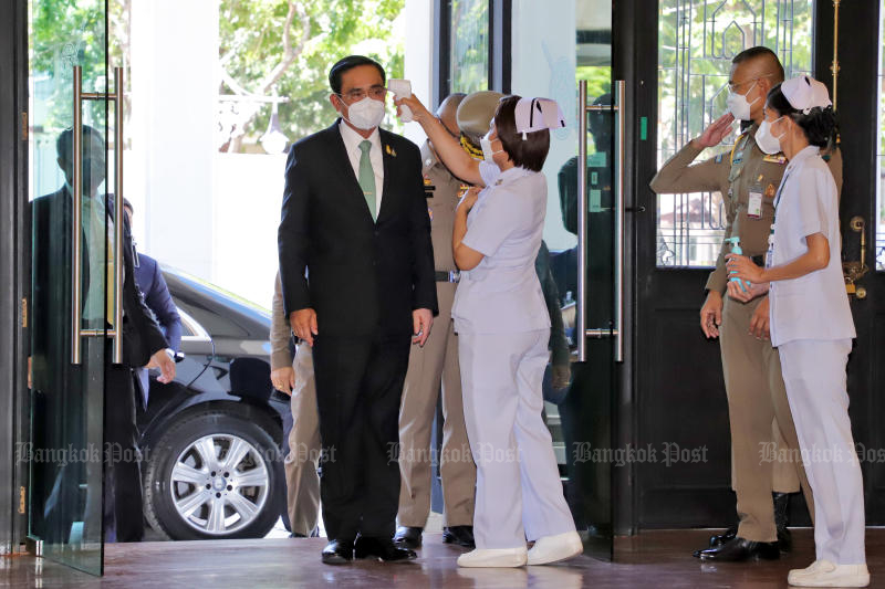 Premierminister Prayuth Chan o-cha lässt sich Fieber messen, bevor er am Montag den Vorsitz der Polizeikommissionssitzung im Royal Thai Police Office führt.