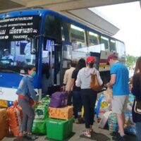 Touristen steigen in einen thailändisch-laotischen Bus in der Provinz Nakhon Phanom
