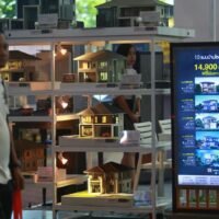 Ein Mann geht an Miniaturmodellhäusern vorbei, die auf einer Haus- und Eigentumswohnungsmesse ausgestellt sind.