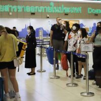 Reisende stehen am Flughafen Don Mueang in Bangkok an, um bei den Transportunternehmen einzuchecken.