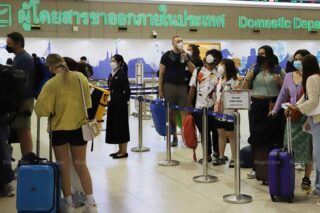 Reisende stehen am Flughafen Don Mueang in Bangkok an, um bei den Transportunternehmen einzuchecken.
