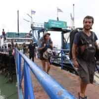Touristen gehen von Bord einer Fähre, die von Raja Ferry betrieben wird und Verbindungen nach Ko Phangan anbietet