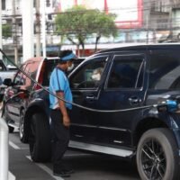 Ein Autofahrer und ein Begleiter unterhalten sich an einer Tankstelle in Bangkok.