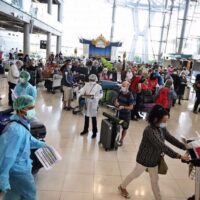 Internationale Besucher warten im Ankunftsterminal des internationalen Flughafens Suvarnabhumi auf Anweisungen von Gesundheitsbehörden,