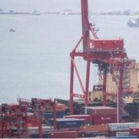 Container stehen gestapelt neben Portalkranen im autonomen Hafen von Sihanoukville in Sihanoukville, Kambodscha.