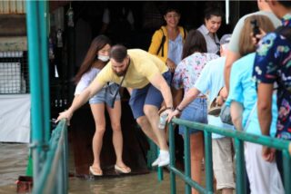 Ein Tourist versucht, dem Wasser am Pier von Tha Tien auszuweichen, während der Fluss Chao Phraya weiter anschwillt