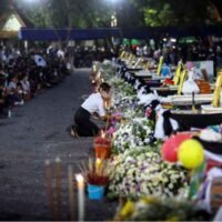 Eine Person zollt am Tag einer Einäscherung im Tempel Wat Rat Samakee nach einer Massenerschießung in einer Kindertagesstätte in der Gemeinde Uthai Sawan den Särgen der Opfer Tribut.