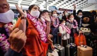 Passagiere, die Teil der ersten aus Thailand ankommenden Touristengruppe sind, posieren am Mittwoch am internationalen Flughafen Taoyuan in Taoyuan für die Medien