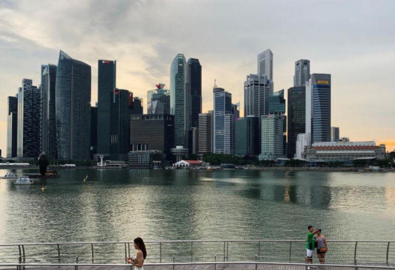 DATEIFOTO - Passanten halten ihre Mobiltelefone, während Menschen mit einem Smartphone ein Selfie-Foto mit der Skyline von Singapurs zentralem Geschäftsviertel in Singapur machen, 10. Mai 2019. (Reuters)