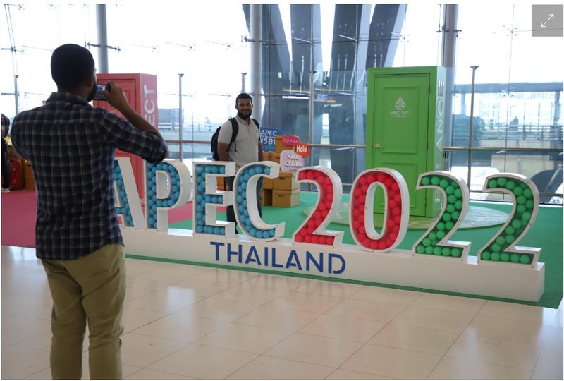 Touristen machen Fotos mit einem Schild für den Gipfel Apec 2022 am Flughafen Suvarnabhumi