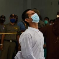 Ein Mann, der beschuldigt wird, schwulen Sex zu haben, wird am 28. Januar 2021 von einem Mitglied der Scharia-Polizei in Banda Aceh öffentlich mit dem Stock geschlagen