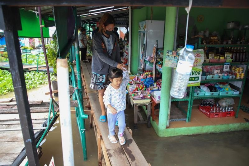Bewohner gehen auf einem provisorischen Gehweg in der Gemeinde Bang Talat 1-Pak Dan in Pak Kret, Provinz Nonthaburi, nachdem der Wasserstand des Chao Phraya-Flusses gestiegen ist und die Gemeinden an seinen Ufern überschwemmt hat. Varuth Hirunyatheb